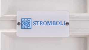 A white door with a sign that reads 'STROMBOLI' and a decorative blue emblem. - Room 'Stromboli' with Sea View, Wi-Fi and Air Conditioning (Pace del Mela)