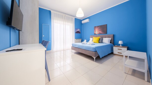 A modern bedroom with a bed, bedside table, and a desk with a chair. - Room 'Stromboli' with Sea View, Wi-Fi and Air Conditioning (Pace del Mela)