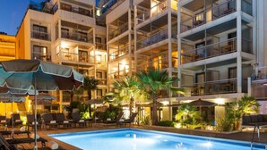A multi-story hotel with a swimming pool, outdoor seating, and palm trees. - Honeymoon Suite in Cannes (Cannes)