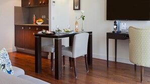 A modern kitchen with wooden cabinets, a dining table with chairs, a small side table with a coffee machine, and a flat-screen TV on the wall. - Honeymoon Suite in Cannes (Cannes)