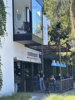 A modern building with a cafe named 'counterpoint' on the ground floor. There are outdoor seating areas with blue pendant lights.
