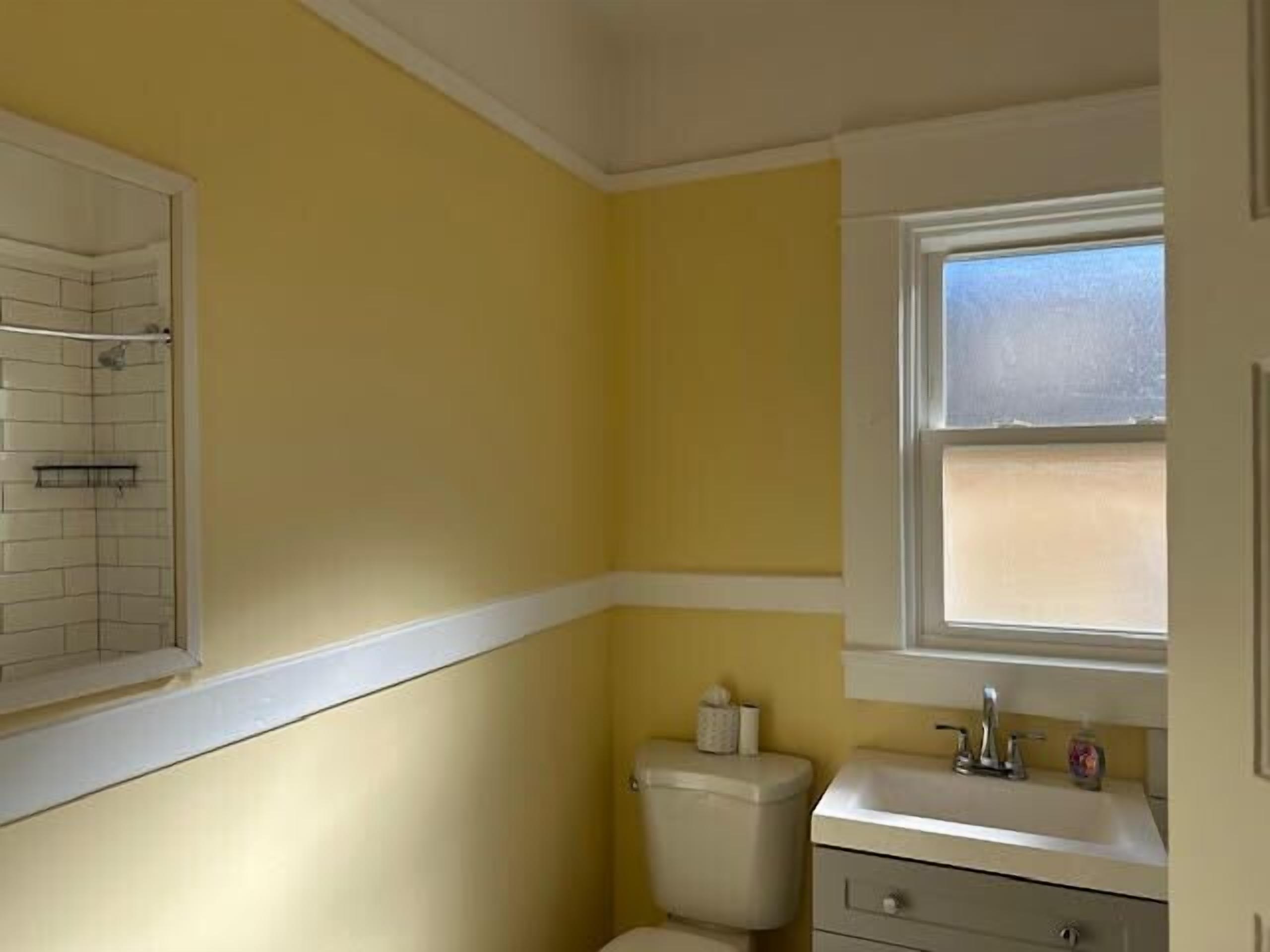 Une petite salle de bain avec des toilettes, un lavabo et une fenêtre.
