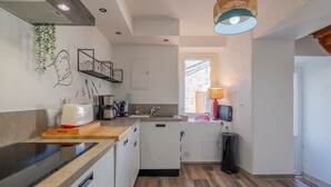 Cocina compacta con tostadora, cafetera y una planta colgante.