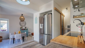 Una cocina moderna con un refrigerador de acero inoxidable, una tabla de cortar de madera y un comedor con mesa y sillas.