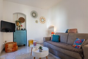 Un salon comprenant un canapé, un téléviseur, un meuble et des œuvres d’art décoratives accrochées au mur.