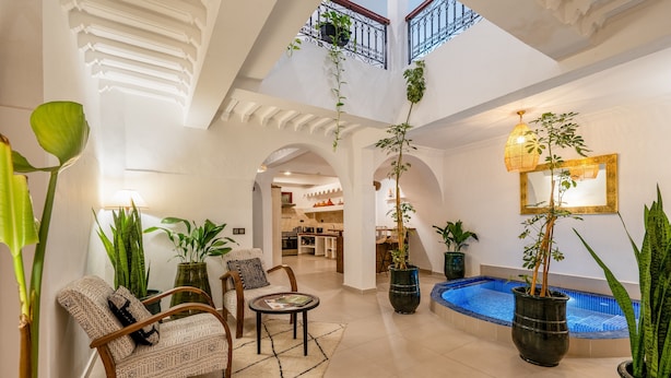 A spacious indoor area with a pool, multiple seating areas, and a view of the kitchen in the background. - PRIVATE RIAD DAR TOURIA (Marrakesh)