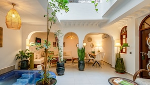 A spacious indoor area with a pool, potted plants, seating, and a dining area. - PRIVATE RIAD DAR TOURIA (Marrakesh)