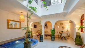 A spacious indoor area with a pool, potted plants, seating areas, and a balcony. - PRIVATE RIAD DAR TOURIA (Marrakesh)