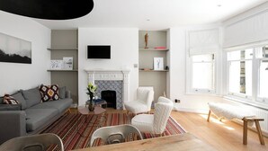 Un salon moderne avec une cheminée, un canapé, un téléviseur et un coin repas.