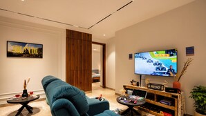 A modern living room with a large flat-screen TV, a blue sofa, a small coffee table, and a wooden entertainment unit. - LiveAway Gurugram by PACK (Gurugram)