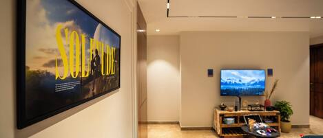 A modern living room with a large poster, a flat-screen TV, and a cozy seating area.