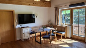 A cozy kitchen with wooden beams, a large TV, and a dining area with a bench and chairs. - Matthiasgut - Tauernview S (Radstadt)