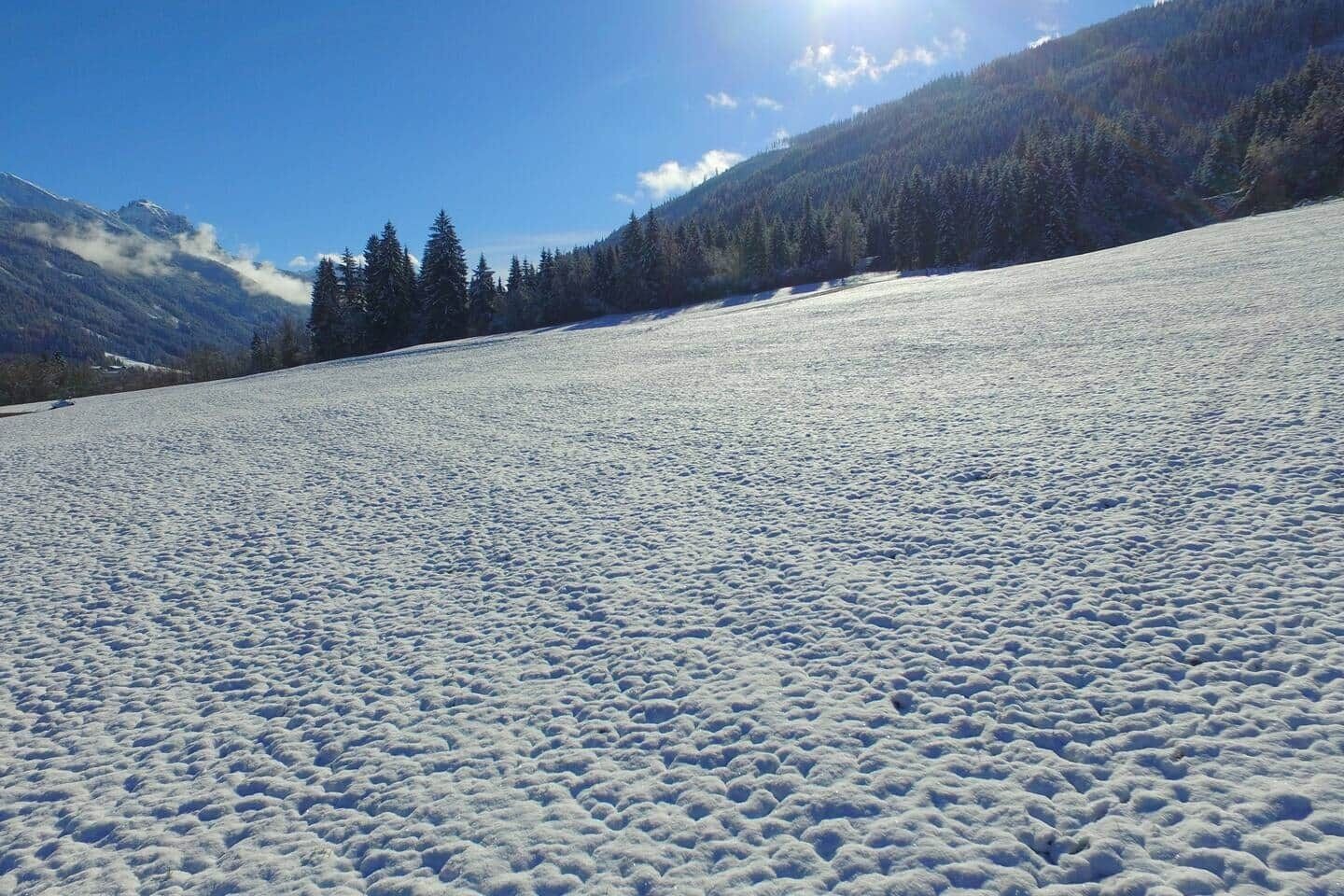 Campo coberto de neve com uma montanha ao fundo.