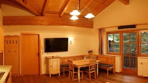 A cozy kitchen with wooden beams, a dining table, and a TV mounted above it. - Matthiasgut - Tauernview S (Radstadt)