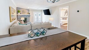 Un salon moderne avec un canapé, une cheminée et une table à manger agrémentée de vases en verre aux motifs géométriques.