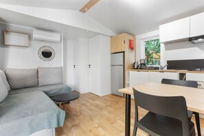 A modern kitchen with white cabinets, a built-in oven, and a window with a view of greenery.