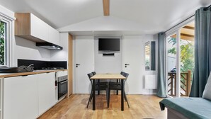 A compact kitchen with a dining table, a flat-screen TV, and a sofa. - Apartment 'Mobile Home Le Montourey' with Balcony and Air Conditioning (Fréjus)