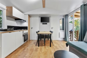 A compact kitchen with a dining table, a flat-screen TV, and a sofa.