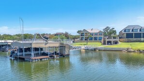 A waterfront property with a dock, a swimming pool, and a large house with multiple balconies.
