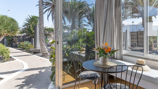 Un patio con mesa, sillas y vistas a palmeras y un jardín.