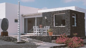A modern house with a stone facade, a white exterior, and a patio with a table and chairs. - Holiday Apartment 'Suite Arte y Dragos' with Mountain View, Wi-Fi and Air Conditioning (San Bartolomé)