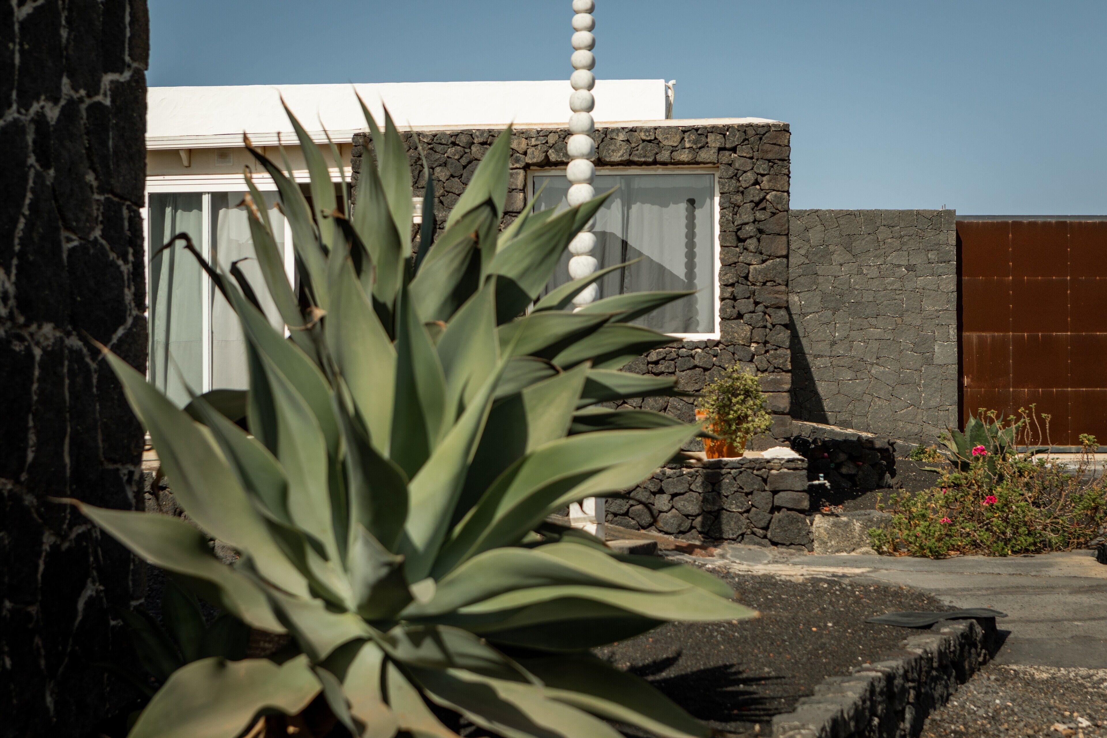 Un bâtiment moderne avec une façade en pierre, un mur extérieur blanc et un portail marron.