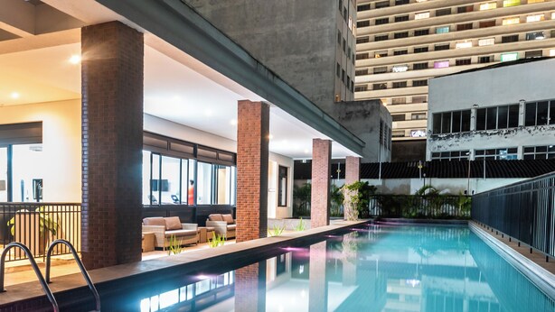 Area piscina dal design moderno, con zona relax e divani, oltre a una ringhiera.