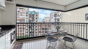 Una cucina moderna con un balcone, ampie finestre e un'area pranzo con sedie in metallo.
