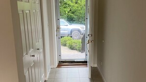 A hallway with a tiled floor leading to a door with a view of a parked car outside. - Charming 3-bedroom house next to Six Flags and Military Base in Gurnee (Gurnee)