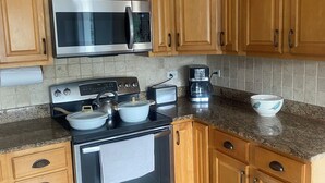 A kitchen with wooden cabinets, a stainless steel microwave, a stove, and a coffee maker. - Charming 3-bedroom house next to Six Flags and Military Base in Gurnee (Gurnee)