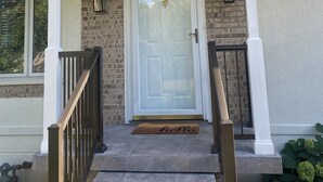 A house with a front porch, a white door, and a brick wall. - Charming 3-bedroom house next to Six Flags and Military Base in Gurnee (Gurnee)
