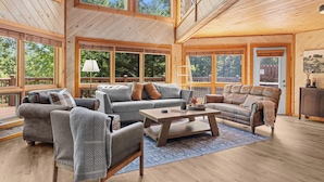 A spacious living room with large windows, wooden floors, and a high ceiling. - Gated Resort Setting*WiFi*Spacious*Hot Tub (Sevierville)