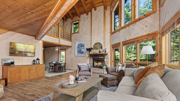 A spacious living room with a fireplace, wooden furniture, and large windows. - Gated Resort Setting*WiFi*Spacious*Hot Tub (Sevierville)