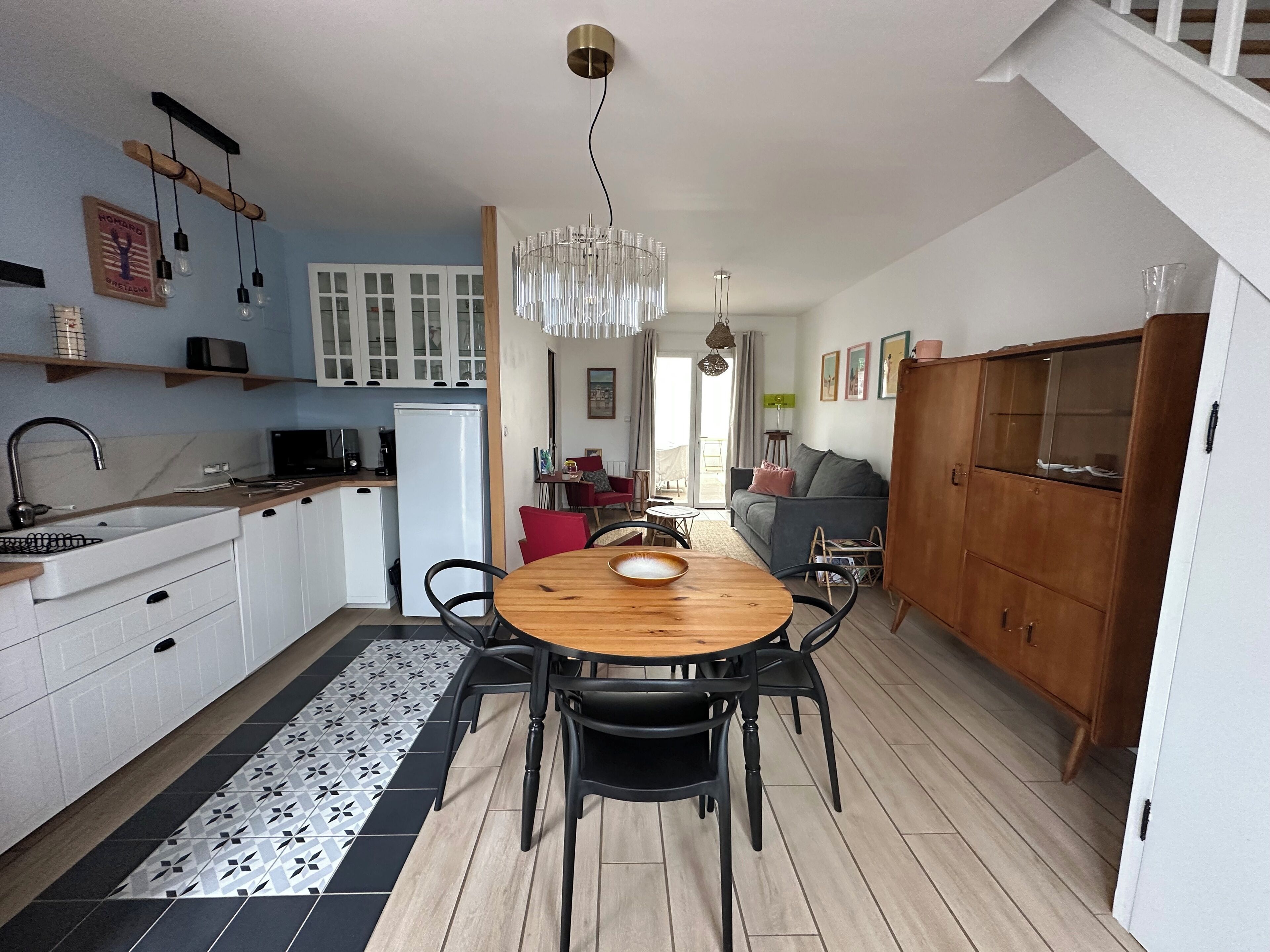 Una cucina moderna con mobili bianchi, un tavolo da pranzo in legno e una sedia nera.