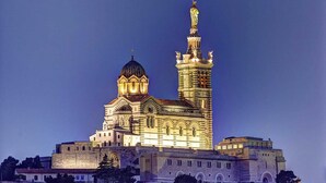 Ein großes, beleuchtetes Gebäude mit einer markanten Kuppel und einem hohen Turm mit Statuen.