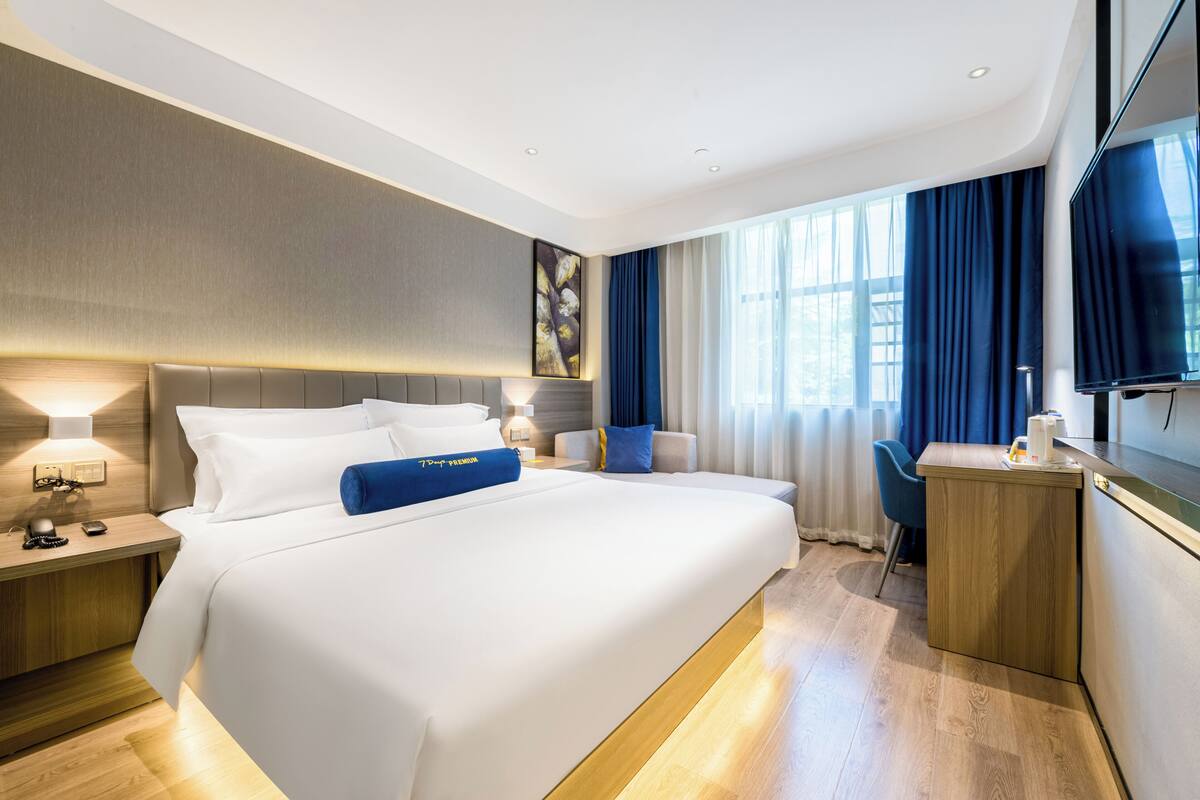 A modern hotel room with a large bed, bedside tables, a desk, and a television.