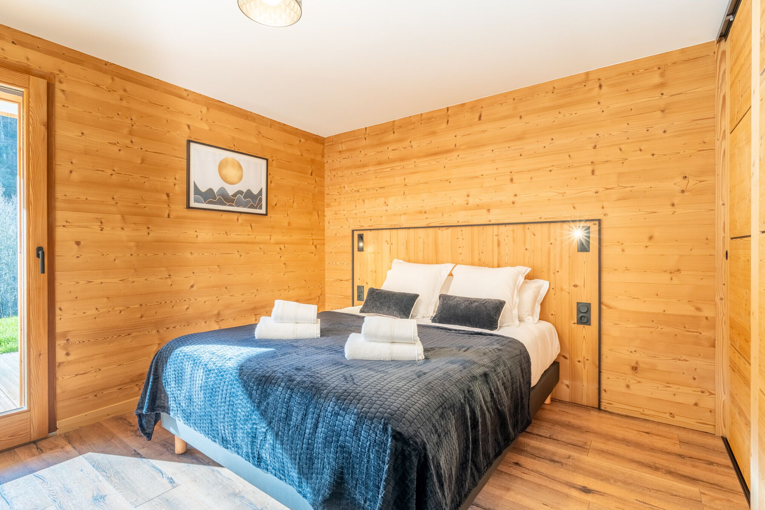 Un dormitorio con paneles de madera, una cama, almohadas y un cuadro en la pared.