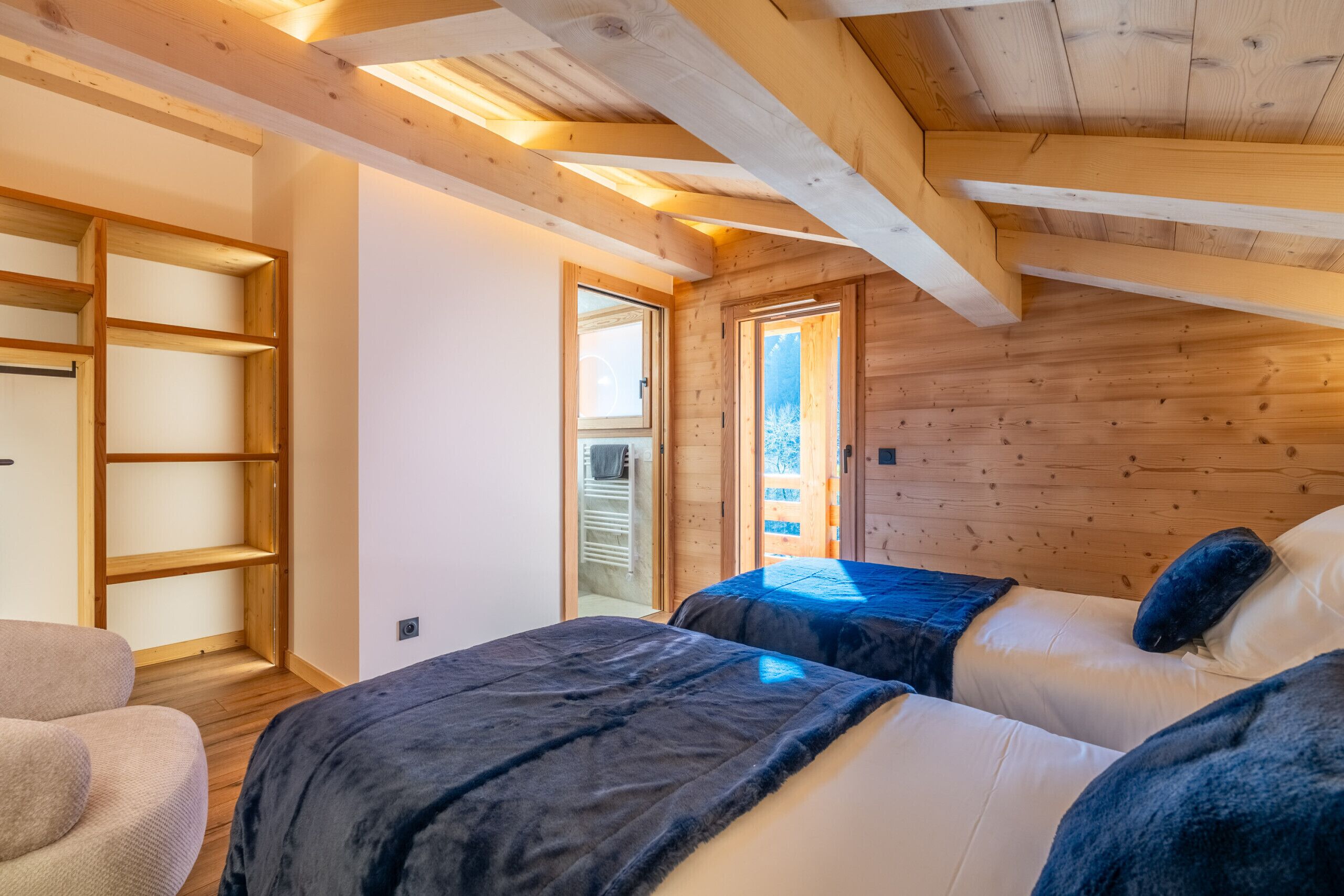 Quarto aconchegante com duas camas, vigas de madeira e um claraboia.