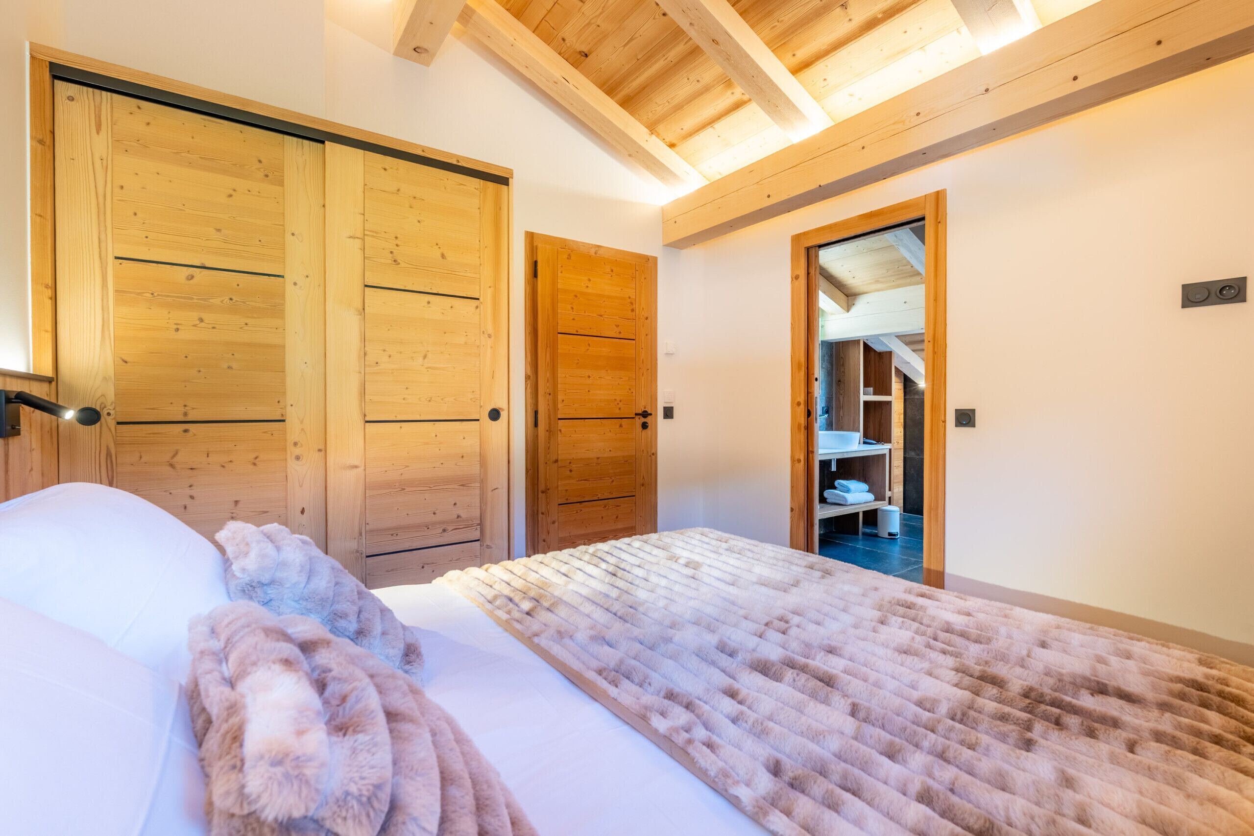 A bedroom with a bed, wooden wardrobe, and a closet with shelves.