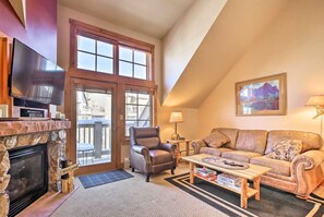 A cozy living room with a fireplace, a leather armchair, a sofa, and a painting on the wall.
