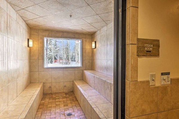 A steam room with a view of trees through a window, benches, and a sign indicating the room's name.