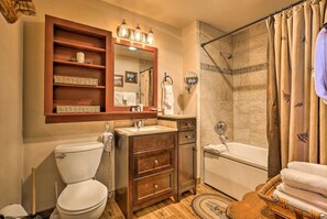 A bathroom with a toilet, sink, vanity, and shower.