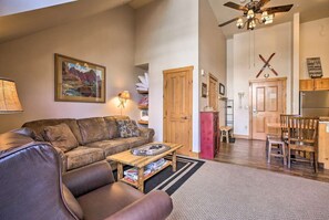 A living room with a brown leather sofa, wooden coffee table, and a painting on the wall. - Keystone Studio Vacation Retreat,Hot tubs,pool,etc (Keystone)