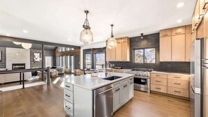 Une cuisine moderne dotée d’un grand îlot central, d’appareils électroménagers en acier inoxydable et d’armoires en bois.
