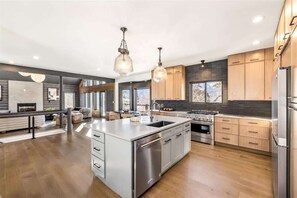 A modern kitchen with a large island, stainless steel appliances, and wooden cabinets.