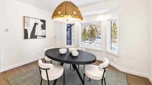 Un coin repas comprenant une table ronde, quatre chaises et un luminaire suspendu.