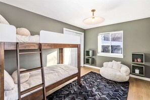 Ein Schlafzimmer mit Etagenbett, einer Schlafcouch, einem Fenster und einer grünen Wand.