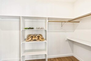 A white closet with multiple shelves and a wooden rod.