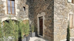 A stone building with a wooden door, a window, and a small archway. - Guest Rooms – Château at lesoleilo.com with Shared Pool from 12/06 to 13/09/2026 (Mostuéjouls)