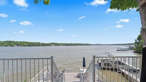 A waterfront property with a dock, a staircase leading to a deck, and a view of a calm lake. - Winding Bay - Lakefront with stellar main channel views! (Sunrise Beach)
